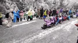 Tourists slide down icy slope after snowfall at Chinese scenic area