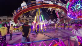 Workers swing on fairground ride to manually power it without electricity