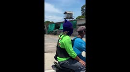 Tiny bird hitchhikes ride on moped in Thailand