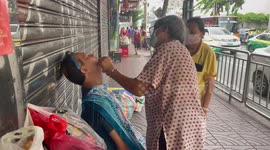 Tourist receives threading treatment for facial hair on 'sidewalk salon' in Bangkok