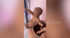 Wild snake pokes out of baby's mouth in family's garden statue