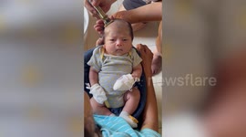 Funny baby boy frowns while parents cut his hair bald