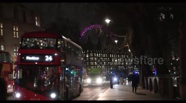 Ambulance driving past, in front of the London Eye and Westminster Abbey, London, United Kingdom