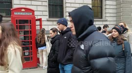 Strange thing curious tourists patiently wait in the queue to have themselves take a photo in a red phone booth, London, UK