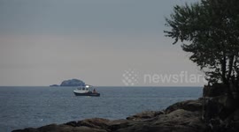 Lobster Fishermen Hauling Traps Off Boston In Early Morning Light With Island Shore In Background