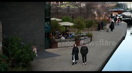 People walking along Regents Canal past the Coal Drops Yard, London, United Kingdom