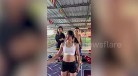 Strong Muay Thai boxing girl lifts two giggly children on her muscular arms