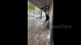 Shop employees battle to prevent rainwater from gushing into store as storm hits Sydney