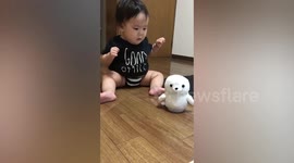 Adorable baby boy fascinated by moving and talking doll