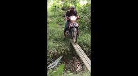 A man riding a motorcycle fell on a thin wood bridge in Indonesia