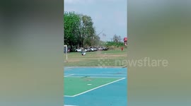 Football players look on in amazement as dust devil tornado picks up umbrella during game