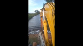 Excavator driver uses vehicle's bucket to row ferry along narrow river in Vietnam