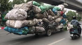 Vietnamese overloaded motorbike catches driver's attention with dozens of large sacks piled up