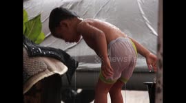 The happiness of a 2 year old child taking a long rain shower in his yard