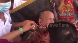 Devotee pierces METAL CHAIN through his cheek for brutal Vegetarian Festival in Thailand