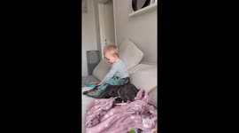 1 year old cuddles with French Bulldog on the sofa