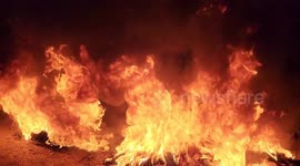 Palestinians burn tires during protest against Israeli military raid that killed 11 and injured 100