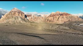 Drone video straight flight toward Wilson Cliffs at Red Rock Canyon near Las Vegas on a cold winter morning with snow on mountains.