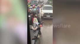 Adorable puppy on motorcycle has towel cloak wrapped around body to stay dry in rain