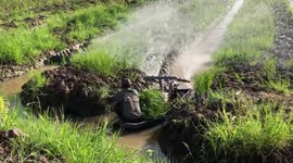 Vietnamese farmer rides boat made from salvaged motorcycle engines to spray water on crops