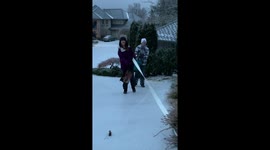 Girls use grocery bags for sledding action in driveway following intense snowstorm
