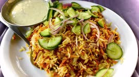 Chicken Biryani lying on a plate and salad  is included in it