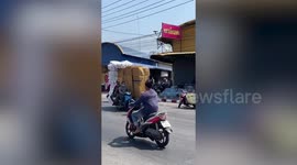 Overloaded motorcycle carries large boxes along road in Thailand