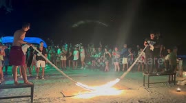 Adventurous tourists jump across burning skipping rope at Thai Full Moon party