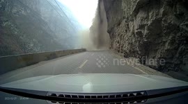 Car reverses to avoid rock and debris tumbling down mountain in China