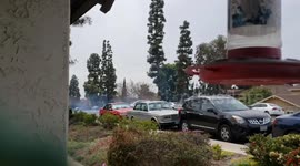 A Car Doing Donuts in A Quiet Neighborhood With Cars Parked On Both Sides of the Street