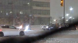 Car Struggles at Intersection During Snowstorm