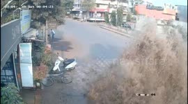 Dramatic CCTV shows biker nearly taken out as water explodes from the road in India