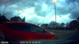 Reckless Driving: Speeding Red Car Gets Sideswiped by Another Vehicle at a Roundabout