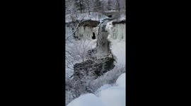 River flows over frozen waterfall at first signs of spring in Minneapolis, Minnesota.