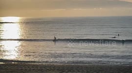 Surfing the waves in Aberystwyth at sunset goldenhour, West Wales, UK