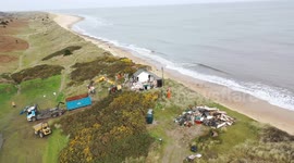 Footage shows construction workers tearing down homes close to a cliff edge - over fears they would fall into the sea