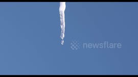 A single ice cycle hanging from a roof melting in the sunshine.
