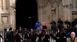 Camilla, the Queen Consort struggles to keep hold of her hat outside Westminster Abbey
