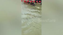 Wild monitor lizard swims next to passing tourist boat on canal in Thailand