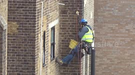 Workman spotted hanging on the ropes on a wall of a residential block of flats  in Earls Court
