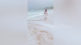 Tourist falls on crashing waves while taking pictures at the beach