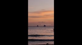 Beautiful sunset scene with sail boats, paddle boarder and people walking in Boracay