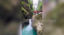 Nervous tourist slips off rock while jumping down waterfall
