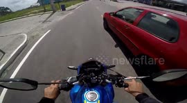 Close Call: Biker Narrowly Avoids a Serious Collision with a Red Car