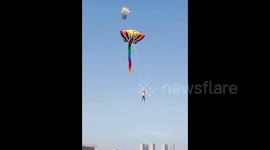 Chinese man soars across sky while flying giant kite during daring stunt