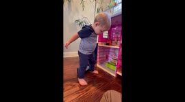 Persistent toddler struggles with using Barbie furniture for himself
