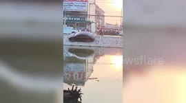 Bungling driver parks sedan along steep riverbank in Thailand