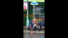 Impressive fail or ingenious hack? Man uses giant umbrella during storm
