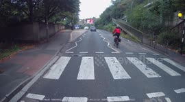 Pedal Cyclist overtakes a bus stopped at a zebra crossing at speed, then turns right from the left turn lane at traffic lights