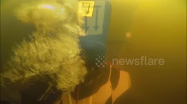 Group of divers retrieve snowmobile from the bottom of a frozen river